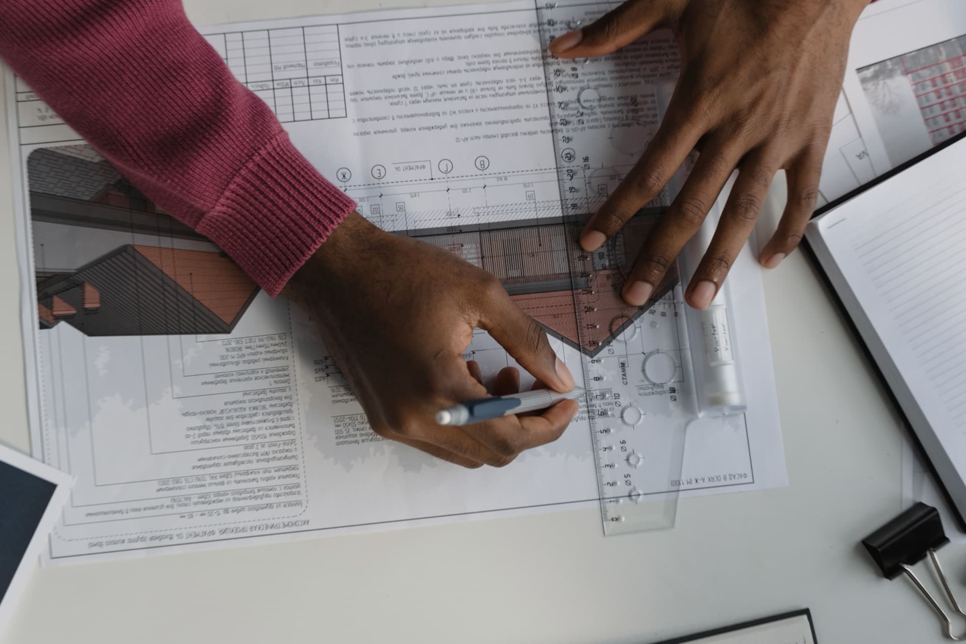 Tekenaar werkt met geodriehoek en potlood een bouwtekening nauwkeurig uit